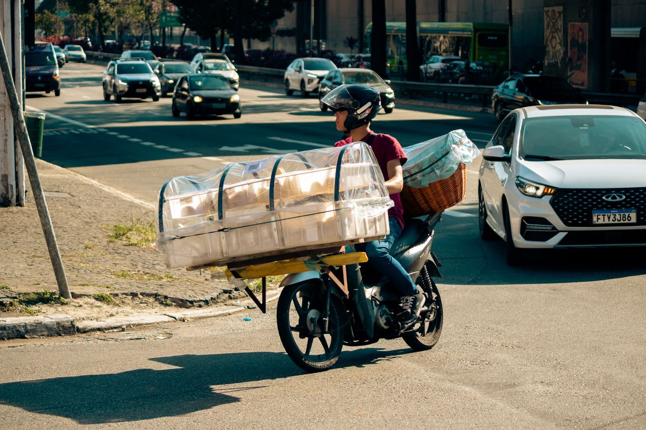 Motorcyclist transporting large packages through urban traffic, showcasing a unique delivery method.
